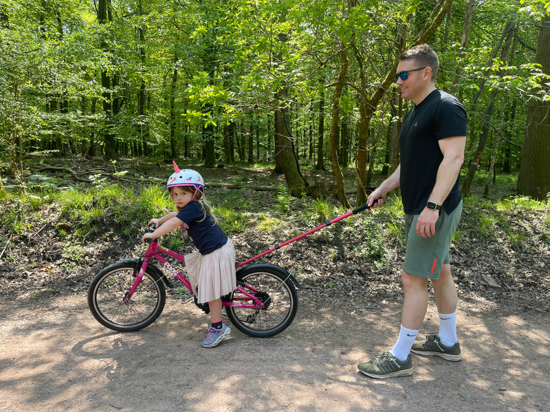 Man walking with a child on a bike in a forest