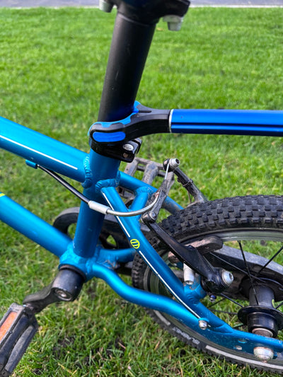 Close-up of a blue bicycle frame with grass in the background